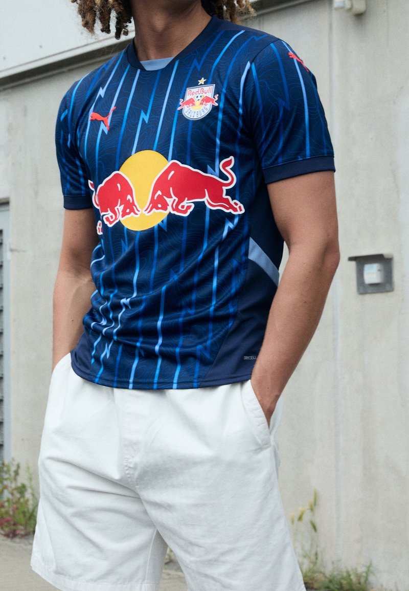 Maglia sportiva blu con strisce verticali, con un grande cerchio giallo e il logo del toro rosso sulla parte anteriore; realizzata in materiale sintetico liscio.