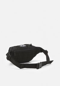 Saco sling preto feito de tecido durável, apresentando uma forma curva, alça ajustável, compartimento com zip e detalhes em padrão de grelha.