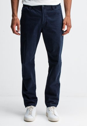 Navy blue chinos made of cotton, featuring a classic cut, side pockets, and a smooth texture, paired with white sneakers.