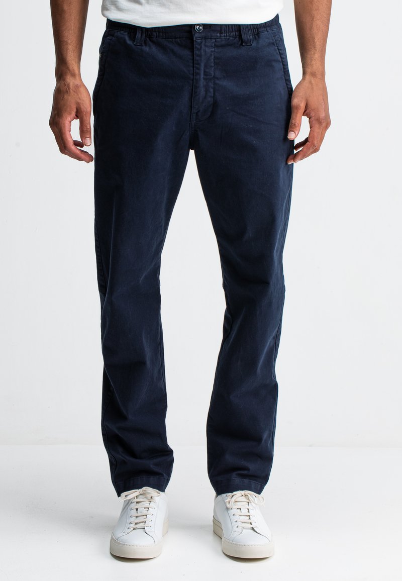Marineblauwe chino's van katoen, met een klassieke snit, zijzakken en een gladde textuur, gecombineerd met witte sneakers.