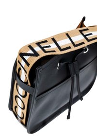 Borsa a tracolla in pelle nera con una larga tracolla beige che presenta testi neri e dettagli bianchi. Chiusura a cordoncino e forma rettangolare elegante.