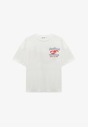 T-shirt oversize blanche avec un graphique de homard et le texte "Expérience de fruits de mer" en bleu et rouge. Manches courtes et col rond.