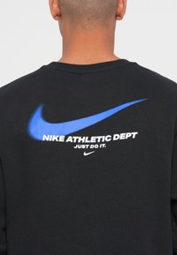 Black sweatshirt featuring a blue Nike swoosh, white text "NIKE ATHLETIC DEPT JUST DO IT" and the Nike logo below. Soft cotton material.