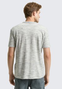 Grijze, korte mouwen t-shirt met een gestructureerd, gestreept patroon. Zachte stof met een ronde hals en een relaxte pasvorm, zichtbare naden bij de schouders en zijkanten.