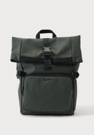 Dunkelgrüner Rolltop-Rucksack mit vorderer Reißverschlusstasche, schwarzem Schnallenriemen und schwarzem Griff auf einfarbigem Hintergrund.