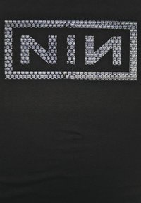 Černé tričko s velkým grafickým potiskem z stříbrných kamínků, na kterém je napsáno "NIN" uvnitř obdélníkového rámečku. Hladká textura s výraznými detaily.