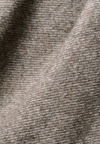 Jasnobrązowy materiał o miękkiej, teksturowanej powierzchni i subtelnym wzorze w kratę, wykonany z wełny lub materiału z domieszką wełny.