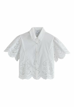 Blouse blanche à manches courtes avec boutons et bords festonnés, broderie ajourée sur les manches et l'ourlet.