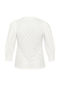 Haut blanc texturé avec un motif en diamant, manches bouffantes longues et encolure ronde. Matière tricotée douce avec une coupe décontractée.