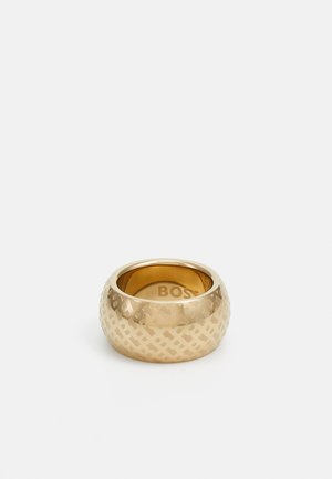 Gouden ring met een ronde vorm en een getextureerd geometrisch patroon. Van binnen gegraveerd met "BOSS." Gladde afwerking met gepolijste randen.