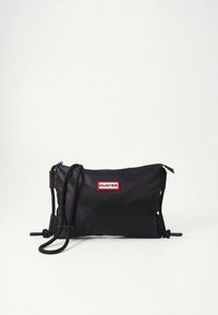 Črna najlonska torbica čez ramo z nastavljivim trakom, z rdečo in belo oznako logotipa "HUNTER", gladke teksture in z zadrgo za zapiranje.