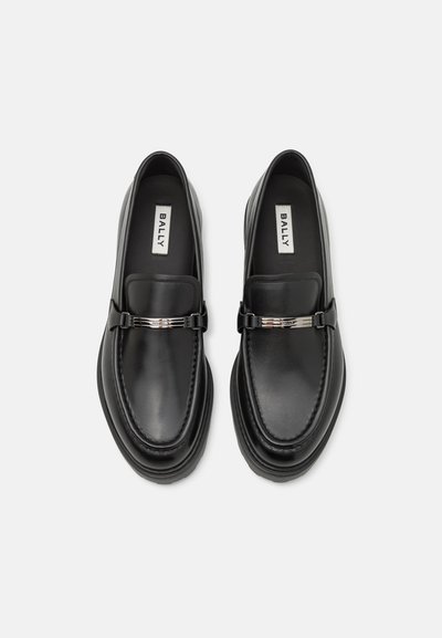 Melni ādas loafers ar gludu apdari, dekoratīvu metāla jostu un kontrastējošu šuvumu. Apaļa purngala forma un nedaudz paaugstināta zole.