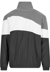 Black and white windbreaker jacket with a mesh upper panel, featuring a stand collar and elastic cuffs at the sleeves.