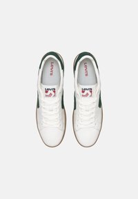 Bela športna obutev z zelenimi dodatki, iz usnja, okrogla konica, enostavna tekstura, na kateri je rdeči Levi's logotip na ježku in strani.