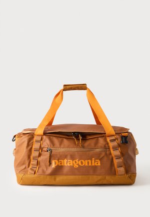 Sac de voyage rectangulaire marron et orange Patagonia avec deux poignées supérieures et une poche frontale zippée.