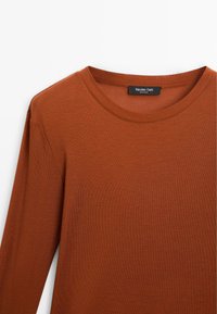 T-shirt a maniche lunghe color ruggine con scollatura rotonda, realizzato in un materiale testurizzato. Etichetta con la dicitura "Massimo Dutti, Made in India."