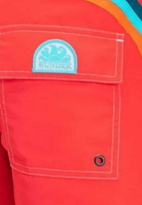 Tessuto rosso con una tasca che presenta un logo "SUNDEK" blu chiaro. Include cuciture bianche e un dettaglio in grommet nero sulla tasca.