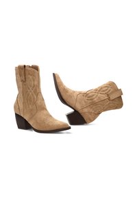 Botas de tobillo de ante color arena con punta afilada, tacón apilado y costuras decorativas en un patrón de infinito. Cierre con cremallera en el lateral.
