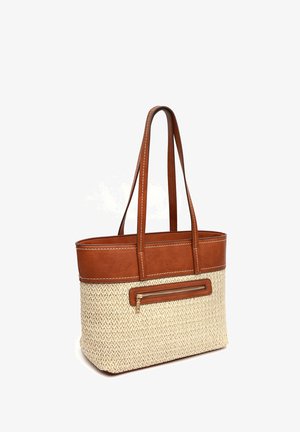 Pruunist nahast detailidega beež kudumiskott pikkade sangade ja esiküljel tõmblukuga taskuga valgel taustal.