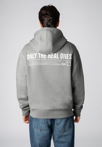 Gray hooded sweatshirt with large white text on the back. Features a relaxed fit, ribbed cuffs, and a kangaroo pocket. Made of soft fabric.