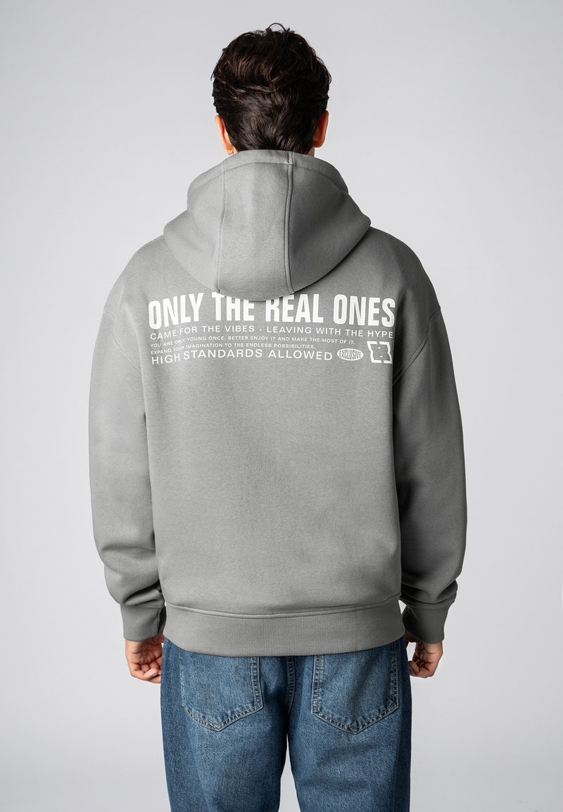 Gray hooded sweatshirt with large white text on the back. Features a relaxed fit, ribbed cuffs, and a kangaroo pocket. Made of soft fabric.