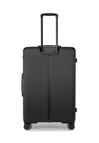 Valise rigide noire avec une surface texturée et rainurée. Équipée d'une poignée télescopique rétractable et de quatre roues pour une meilleure mobilité.