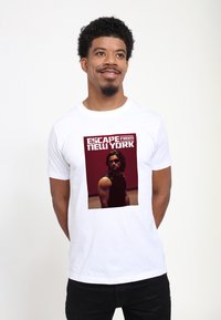 Hvid kortærmet t-shirt med et kvadratisk grafisk motiv af en mand i en sort tanktop, med teksten "ESCAPE from NEW YORK" i fed rød skrift.