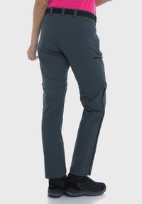 Szare spodnie outdoorowe wykonane z wytrzymałego materiału, o dopasowanym kroju, z zamykanymi na zamek kieszeniami i zwężanymi nogawkami. Dodatkowe akcenty to mankiety zamykane na zamek.