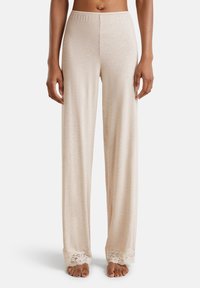 Licht beige pyjamabroek met een losse pasvorm, voorzien van een zachte textuur en kantafwerking aan de onderkant. Elastaan in de tailleband voor extra comfort.