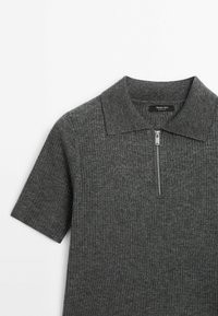 Szara prążkowana koszulka polo z dzianiny, z suwakiem przy kołnierzu i krótkimi rękawami. Materiał jest miękki w dotyku, z subtelnymi odcieniami koloru.