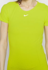 Camiseta de fitness de Nike en vibrante verde lima, de mangas cortas, diseño sin costuras, con pequeño logo blanco en el pecho y acentos texturizados.