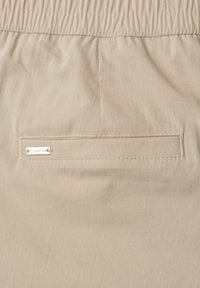 Beige fabric with a horizontal back pocket featuring a small metal tag labeled "Street One" and an elastic waistband above.