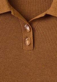 Rjava rebrasta tkanina polo majice z zloženo ovratnico, s tremi svetlimi gumbi na vratu in teksturirano površino.