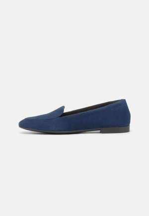 Blå sueksko med spiss tå og lav svart såle. Slett tekstur, minimalistisk design, har slip-on stil.