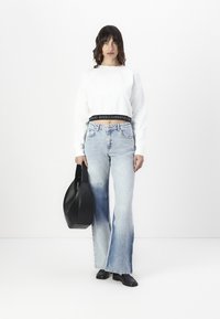 Witte cropped sweatshirt met zwarte logo-band, lichtblauwe flared jeans en zwarte handtas. Soepele stof en casual fit.