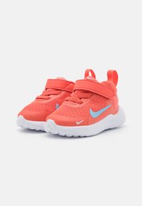 Baskets Nike avec une tige en mesh corail vif, des accents bleus, une sangle ajustable et une semelle en caoutchouc blanche. Bout arrondi avec des détails texturés.