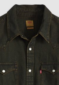 Camicia in denim verde scuro con colletto a punta, bottoni a pressione, due tasche sul petto e un'etichetta rossa Levi's sulla tasca sinistra.