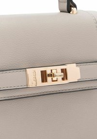 Grijze leren handtas met een gestructureerd ontwerp, voorzien van een gouden sluiting, contrasterende stiksels en een gladde textuur.