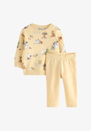 Gul sweatshirt med tegneserieagtige dyr og planter, kombineret med gule leggings. Blødt stof, ribstrikkede manchetter og elastisk talje på bukserne.