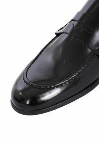 Scarpa da uomo in pelle nera con finitura lucida, punta arrotondata, cuciture decorative e un sottile dettaglio a strappo sulla parte superiore del piede.