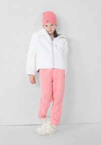 Witte fleece zip-up jas, lichtroze sweatpants, roze gebreide beanie met een logo patch en witte sneakers. Eenvoudige, zachte texturen overal.