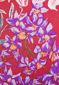 Röd tyg med ett blommönster som innehåller lila och gula blommor, kompletterat med gröna blad. Designen är livfull och detaljerad.