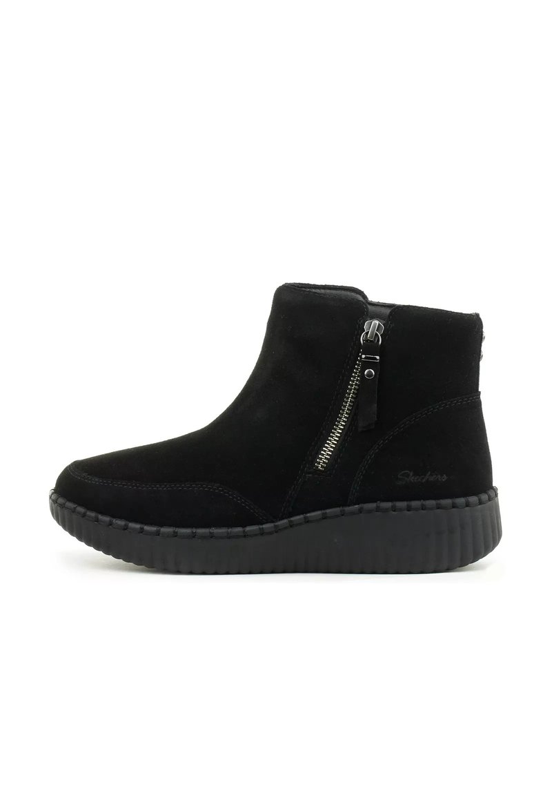 Stivaletti neri in suede con zip laterale, punta arrotondata e suola in gomma testurizzata. Dettagli di cucitura evidenti lungo i bordi.