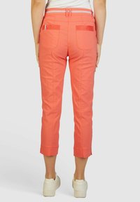 Koraalkleurige cropped broek met een aansluitend ontwerp, riemlussen, twee achterzakken en omslagranden. Gemaakt van glad, duurzaam stof.