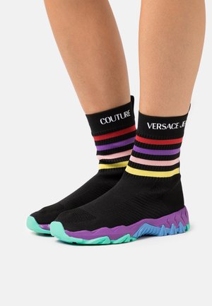 Sneakers in stile calzino nere con accenti a righe multicolore. Presentano una tomaia nera testurizzata e una suola colorata vivace in viola e verde acqua.