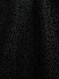 Tissu en dentelle noire avec des motifs floraux complexes, présentant une combinaison de surfaces lisses et texturées. Matériau léger et transparent.