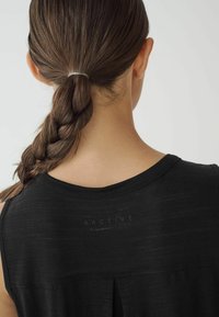 Must pärgamentkammiots, millel on ümar kaelus, volditud seljadetail ja kergelt märkav logo kaela lähedal. Sile tekstuur ja ilma varrukateta disain.