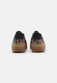 Tenisice s floralnim uzorkom imaju tamnoplavu nubuk gornjište, obloženi svijetlosmeđi potplat i zaobljen dizajn stražnjeg dijela. Značajne su živopisne boje i teksturirana tkanina.