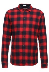 Chemise à carreaux rouge et marine à manches longues en coton. Dispose d'un col classique, de longues manches et d'une fermeture à boutons sur le devant. Petit détail du logo près de la poitrine.