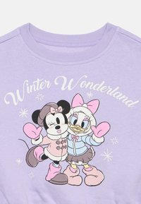 Lila sweatshirt z grafiko dveh risanih likov v zimskih oblačilih, s tekstom "Zimska dežela" nad njimi in akcenti snežink.